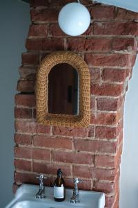 a brick wall with a mirror above a sink at Luxury family and dog friendly cottage in North Norfolk, Aylsham in Aylsham
