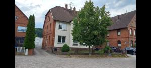una casa con un árbol delante de ella en Haus an der Weser - 24/7 Check-In 