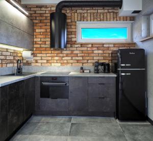 uma cozinha com um frigorífico preto e uma parede de tijolos em Widokówka Kletno em Stronie Śląskie
