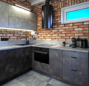 uma cozinha com um fogão, um lavatório e uma parede de tijolos em Widokówka Kletno em Stronie Śląskie