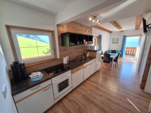 a kitchen with white cabinets and a large window at Lärchenreith Appartement in Schladming