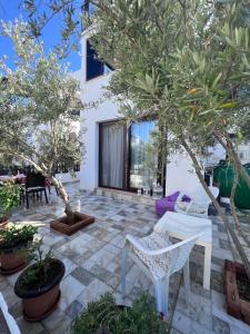 une terrasse avec des arbres, une chaise blanche et une table dans l'établissement Lovely detached private house in Bodrum Bogazici, à Milas