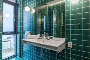 a green tiled bathroom with a sink and a window at Exclusive Beach House Ramberg in Ramberg