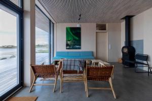 uma sala de jantar com mesa, cadeiras e janelas em Exclusive Beach House Ramberg em Ramberg