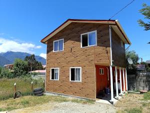 una pequeña casa con una puerta roja en un campo en Cabañas Hornopirén, en Hornopirén