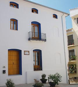 biały budynek z niebieskimi drzwiami i oknami w obiekcie Complejo Rural La Belluga w mieście Segorbe