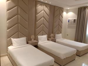 a hotel room with three beds in a room at Dorm Story For Hotel Apartment in Taif