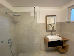 uma casa de banho com um lavatório e um chuveiro com um espelho. em Ferienwohnung Kühar em Maishofen