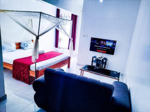 een woonkamer met een bed, een bank en een tv bij Studio at Kisimani Heights Apartment. in Mombasa