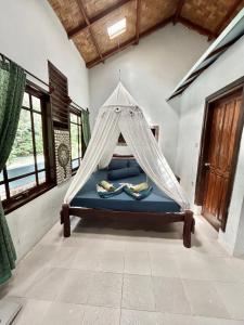a bed with a net in a room with windows at Aussie Inn Bukit Lawang in Bukit Lawang