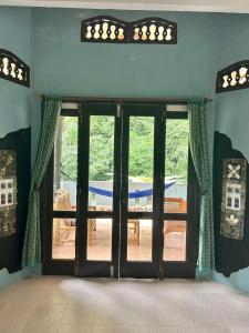 a room with doors with a view of a patio at Aussie Inn Bukit Lawang in Bukit Lawang