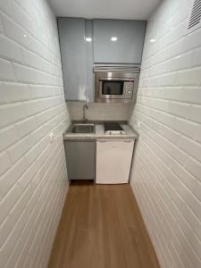 eine kleine Küche mit einer Spüle und einer Mikrowelle in der Unterkunft Resitur Luxury Suit 6 in Sevilla