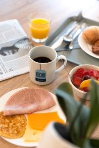 a table with a plate of food and a cup of coffee at Kyriad Chateauroux in Châteauroux