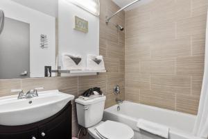 a bathroom with a sink and a toilet and a tub at Restauparc Motel in Casselman +28 photos