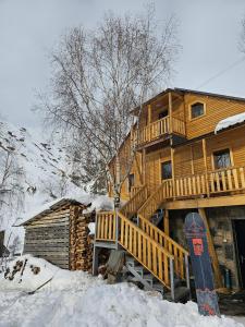 een houten hut met een snowboard in de sneeuw bij Guesthouse Ushguli Maspindzeli in Ushguli