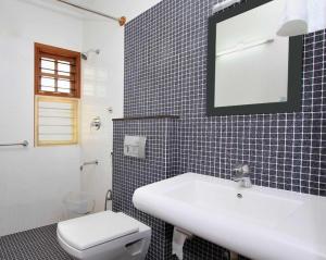 a bathroom with a white sink and a toilet at ZIONS AIRPORT HOTEL in Bangalore