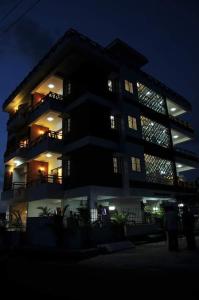 duży budynek z ludźmi stojącymi przed nim w nocy w obiekcie ZIONS AIRPORT HOTEL w mieście Bengaluru