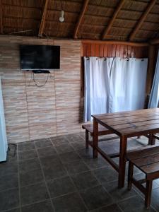 um quarto com uma mesa de madeira e uma televisão e uma mesa sidx sidx em Cabaña frente al mar em Punta Del Diablo