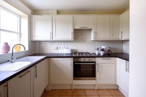 a kitchen with white cabinets and a stove top oven at Guildford Townhouse with Parking in Guildford