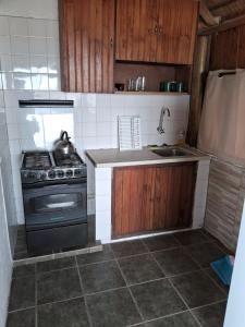 uma pequena cozinha com um fogão e um lavatório em Cabaña frente al mar em Punta Del Diablo