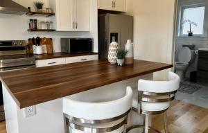 a kitchen with a wooden counter top and white stools at Bambury's Hillside Chalets in Rocky Harbour