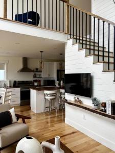a living room with a staircase and a kitchen at Bambury's Hillside Chalets in Rocky Harbour