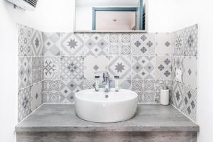 ボルドーにあるAppartement charmant Bordeaux centreのタイル張りの壁、白い洗面台付きのバスルーム