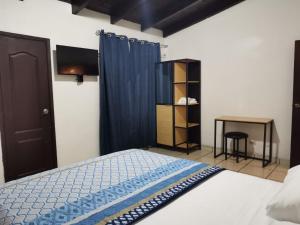 a bedroom with a bed with a blue curtain and a table at Hotel Ghiza in Tegucigalpa