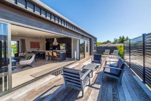 a house with a deck with chairs and a kitchen at Vinebox on Wilson in Martinborough 