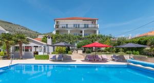 uma casa com piscina com cadeiras e guarda-sóis em Apartments Sorić em Trogir