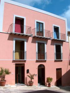 a pink building with balconies and plants in front at Casale Vacanze in Siculiana