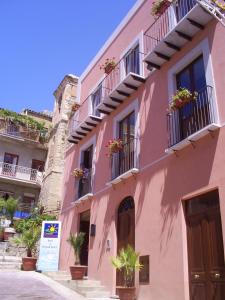 a pink building with potted plants on the balconies at Casale Vacanze in Siculiana