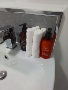 a bathroom sink with two towels and two bottles of soap at Apartment 10, Plants Yard, Bridge Street. in Worksop