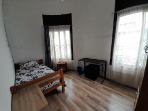 ein Schlafzimmer mit einem Bett und zwei Fenstern in der Unterkunft Hostal Herencia Porteña in Valparaíso