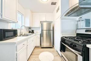 una cocina con nevera de acero inoxidable y armarios blancos en Dual-Level Delight 2BR in Hollywood - BR4-BH en Los Ángeles