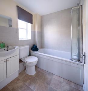 a bathroom with a toilet and a tub and a sink at Guildford Townhouse with Parking in Guildford +16 photos