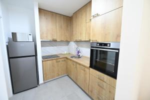 a kitchen with wooden cabinets and a stainless steel refrigerator at Apartman N&D in Banja Luka +21 photos