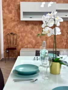 a table with plates and glasses and a vase with flowers at Atelier 1 - Appartamento ad un passo dal mare in Sapri