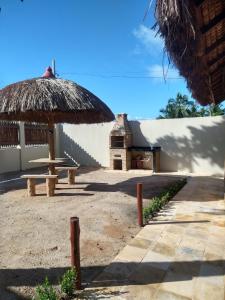 a hut with a table and a straw umbrella at Maragogi Chalés Antunes in Maragogi