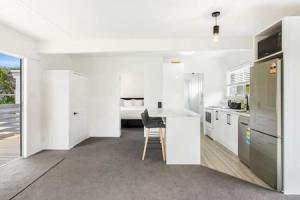 een keuken met witte kasten en een stoel. bij Cockle Bay Getaway is close to beach in Auckland