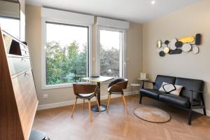 un soggiorno con divano, tavolo e sedie di Appart Hôtel Coraline - Genas Lyon Eurexpo a Genas