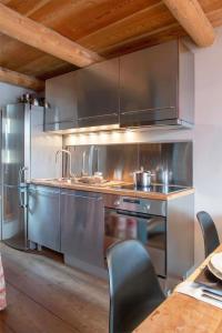 a large stainless steel kitchen with a table and chairs at La Stalla in Vicosoprano