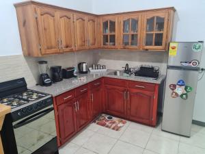 a kitchen with wooden cabinets and a refrigerator at La Rose Apartment in Montego Bay