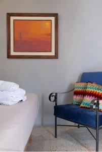 1 dormitorio con una silla azul y un cuadro en la pared en Hostel Casa Betancourt en Salinas