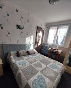 een slaapkamer met een bed met een quilt bij Hôtel les Deux Cols in Sainte-Marie-de-Campan