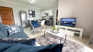 Una sala de estar con un sofá azul y un televisor. en Umhlanga Cosy Apartment, en Durban