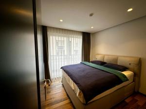 - une chambre avec un lit et une grande fenêtre dans l'établissement Stylish Downtown Apartment, à Pristina