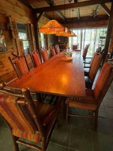 een grote houten tafel en stoelen in een kamer bij Spectacular Seven Keys Camp on Pristine Loon Lake 