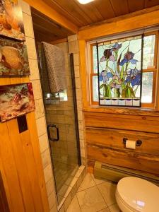 een badkamer met een douche, een toilet en een raam bij Spectacular Seven Keys Camp on Pristine Loon Lake 