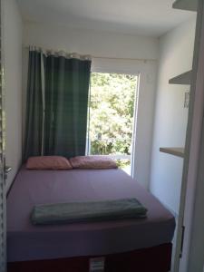 a small bedroom with a bed with a window at Apartamentos PRAIA DE BOMBAS in Bombinhas